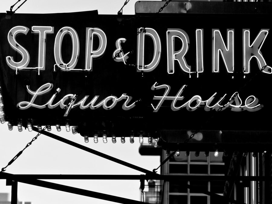 Black and white photo of an old neon business sign that reads Stop and Drink in large straight text and Liquor House in smaller cursive font