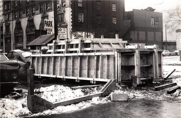 A large wooden framework around an unidentifiable object outdoors in the middle of winter. The frame resembles a tank.