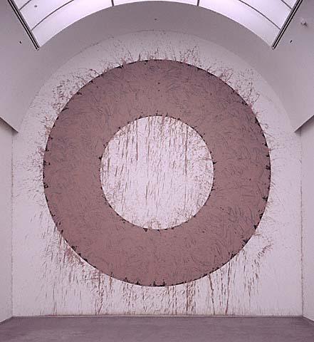 A brown ring on a tall wall with an arched ceiling. Lots of splatter marks fill the white spaces around and in the circle.