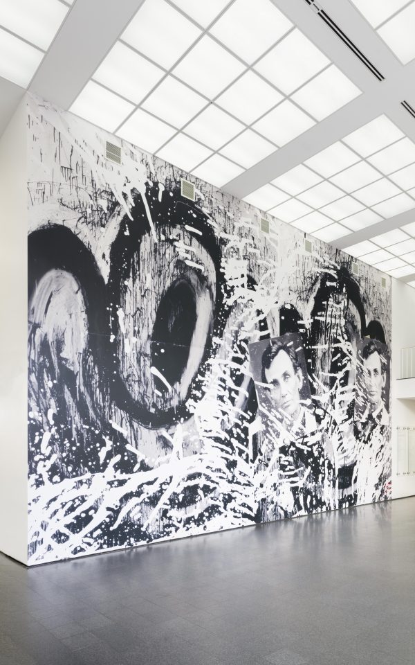 An image of a huge photographic wallpaper mural in the MCA's second floor lobby featuring cartoonish eyes, two photographs of Abraham Lincoln, and splatters of black and white paint.