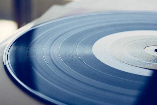 A vinyl record disc is cropped in half, its center is aligned with the right side of the image.