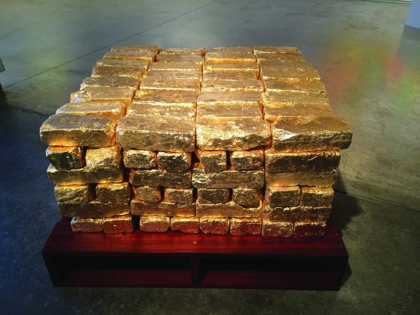 Six rows of gold-leafed bricks are stacked atop a wooden pallet.