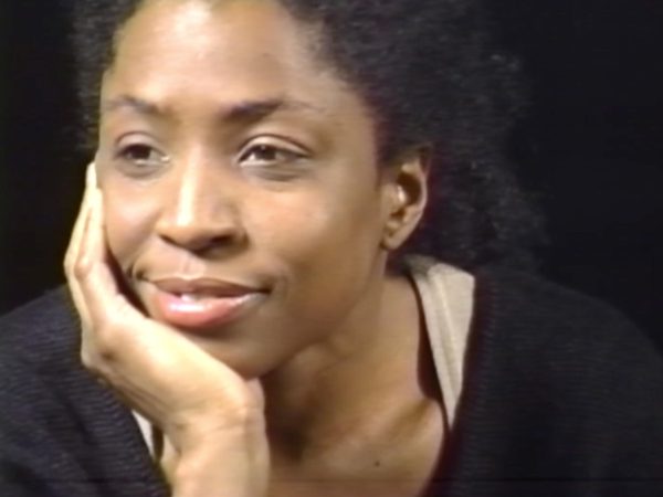 Close up of a female-presenting person resting their chin in their right hand while looking off into the distance