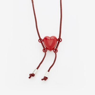 A red cord with a red heart pendant has four clasps, two on each side that make it look like a heart holding onto a swing with legs swinging to left.