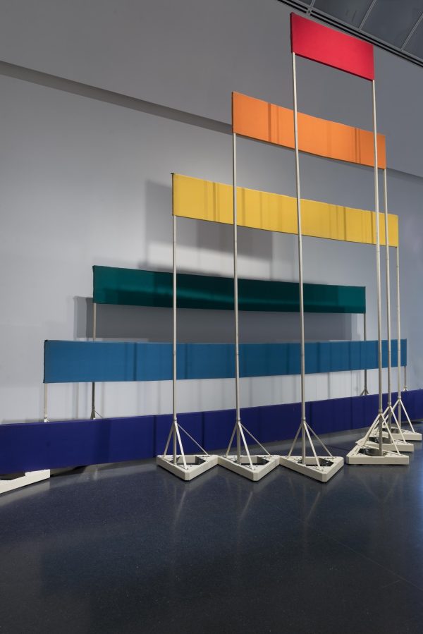 Six boards, each a different color and length, are supported by stands of increasing height and decreasing width.