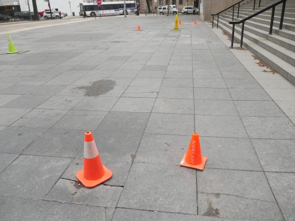 Long view of several brightly colored hazard cones on gray pavement tiles