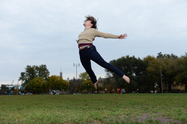 A person jumps leaning forward in mid air, with arms and legs stretched backwards.