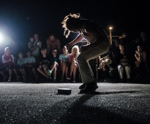 One spotlight highlights a person in a chair position as if they were caught post jump in front of an audience