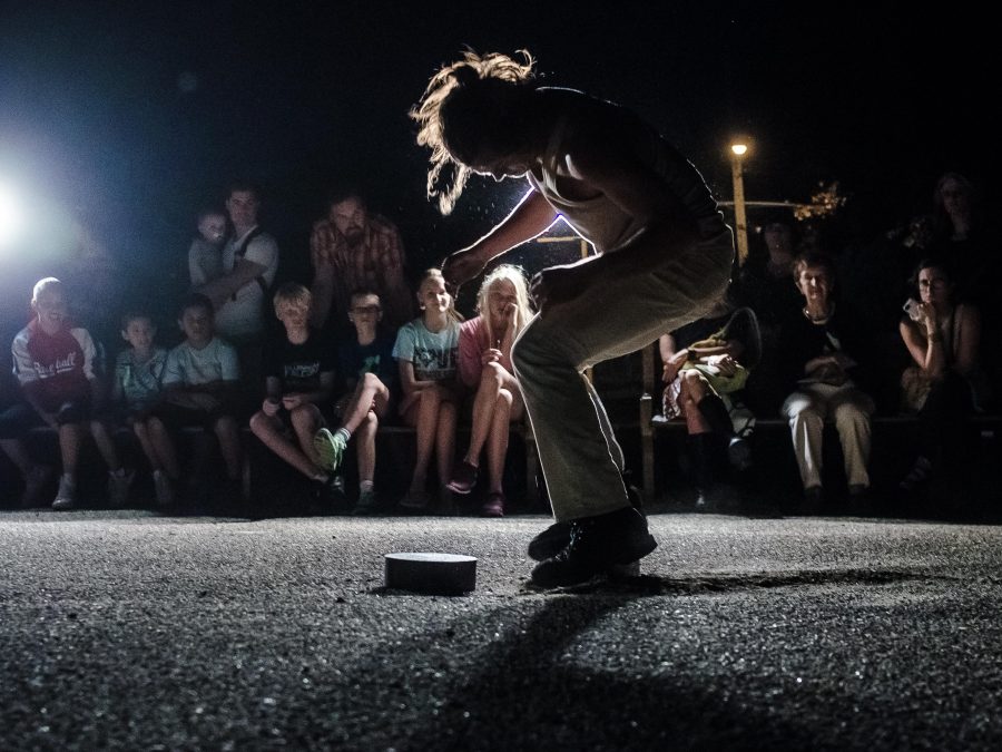 One spotlight highlights a person in a chair position as if they were caught post jump in front of an audience