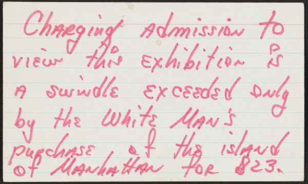 A ruled index card with red handwritten text reads 