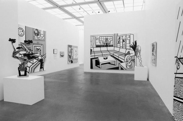 Black and white paintings and sculptures in a gallery space