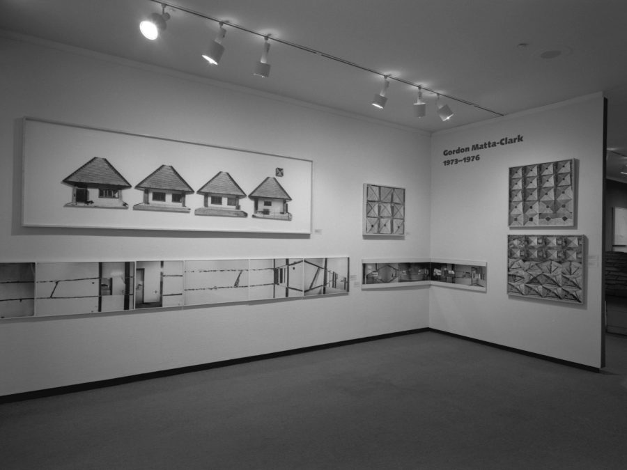 Black and white photo of a gallery installation with artworks spanning two walls