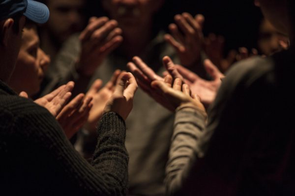 Close up of many sets of hands, palms facing up, from a group standing in a circle