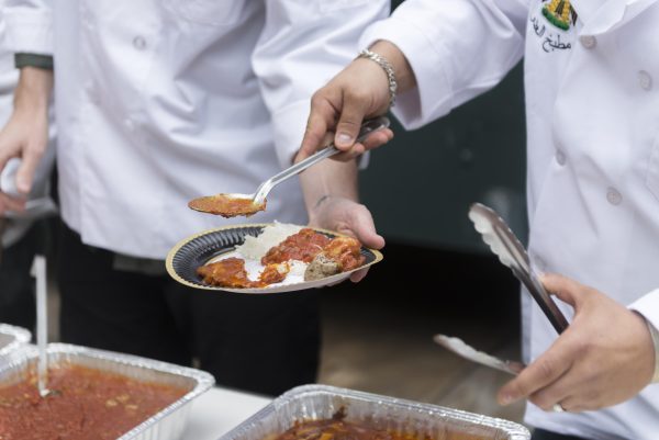 A person scoops a red sauce from a plate that someone else is holding