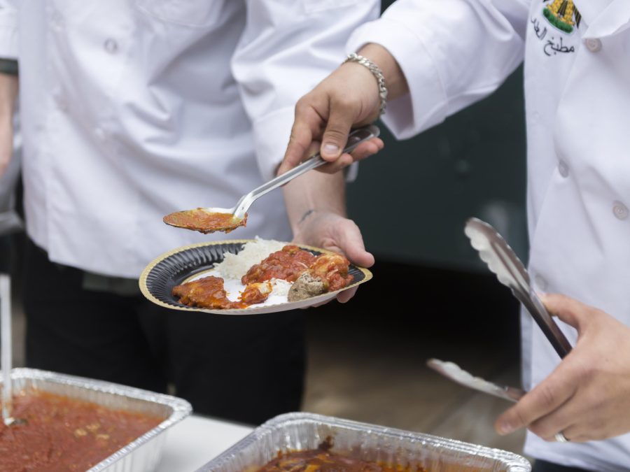 A person scoops a red sauce from a plate that someone else is holding