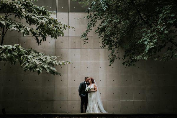 A couple poses for an intimate photo with the MCA facade serving as a backdrop