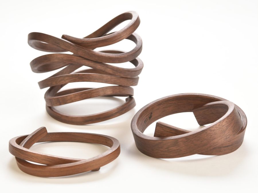Three wooden bracelets of varying thicknesses are each shaped into distinct spirals.