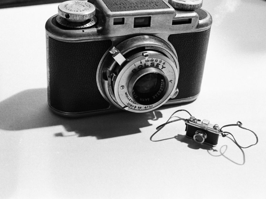 A black-and-white photo shows a film camera next to a much smaller version of itself.
