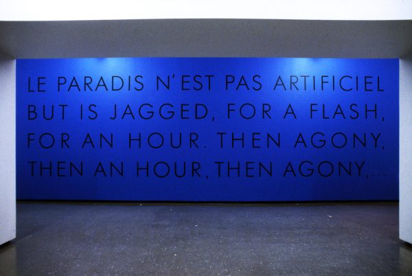 Blue text on a blue wall reads Le paradis n'est pas artificiel but is jaggeded for a flash, for an hour, then agony, then an hour, then agony.