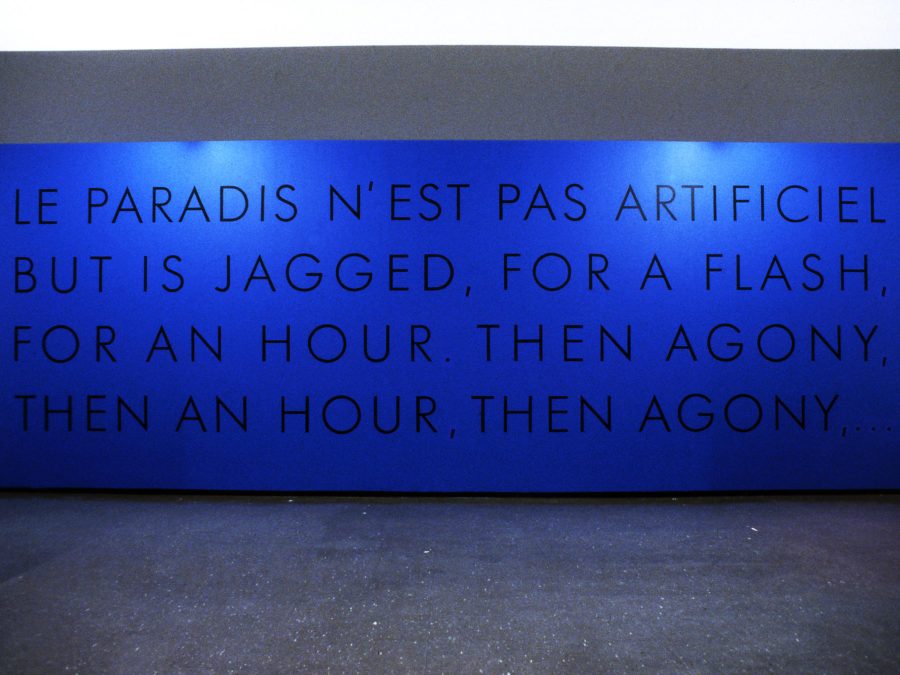 Blue text on a blue wall reads Le paradis n'est pas artificiel but is jaggeded for a flash, for an hour, then agony, then an hour, then agony.