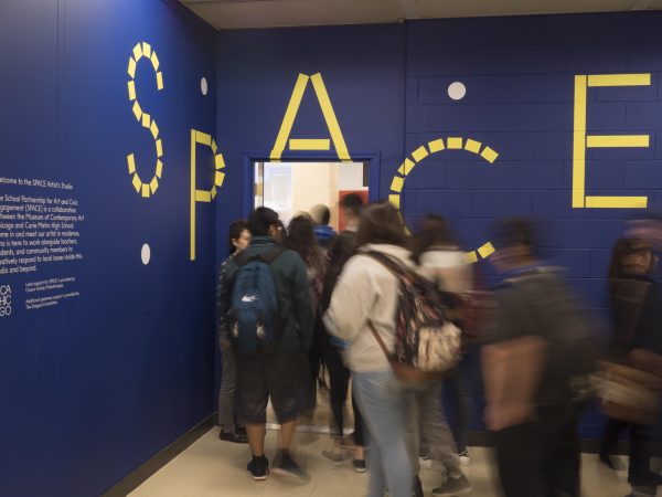 Long exposure shot of people walking through a doorway with the word Space painted in large font above it