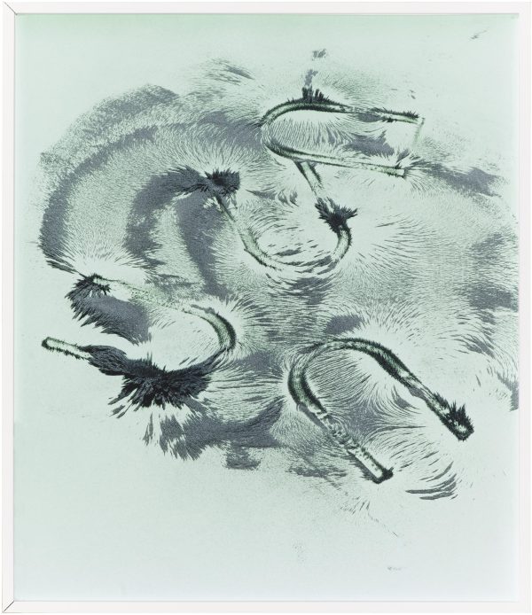 Grey paint seems to be spread around in a circle on a white surface by four u-shaped objects