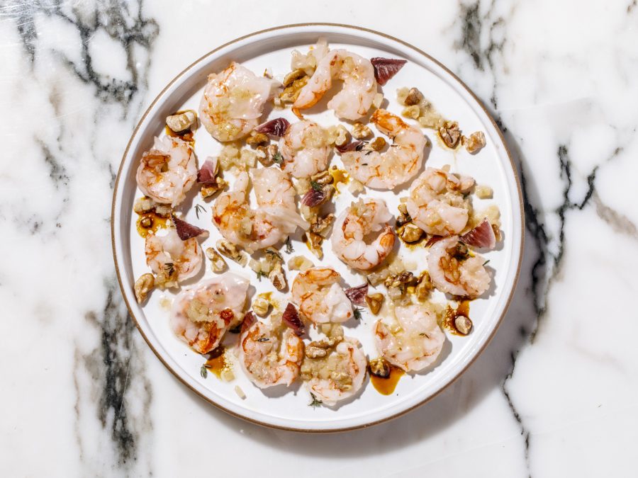 A delicate, artistically plated dish served on a white plate atop a white marble surface.