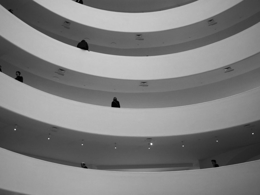 Taken from a lower level looking up, a black-and-white photo shows four levels of a building that curve inwards.