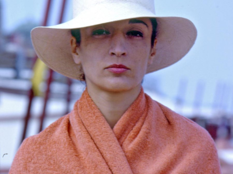 A portrait shows a light-skinned person wearing a large, wide-brimmed white hat and an orange shawl or blanket.