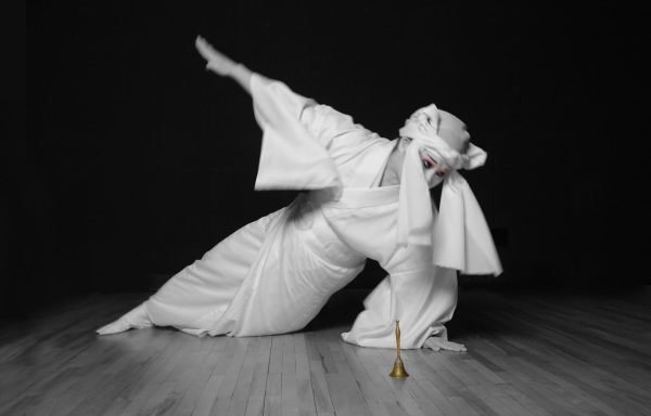 a dancer in a white kimono posing in a one-handed side plank