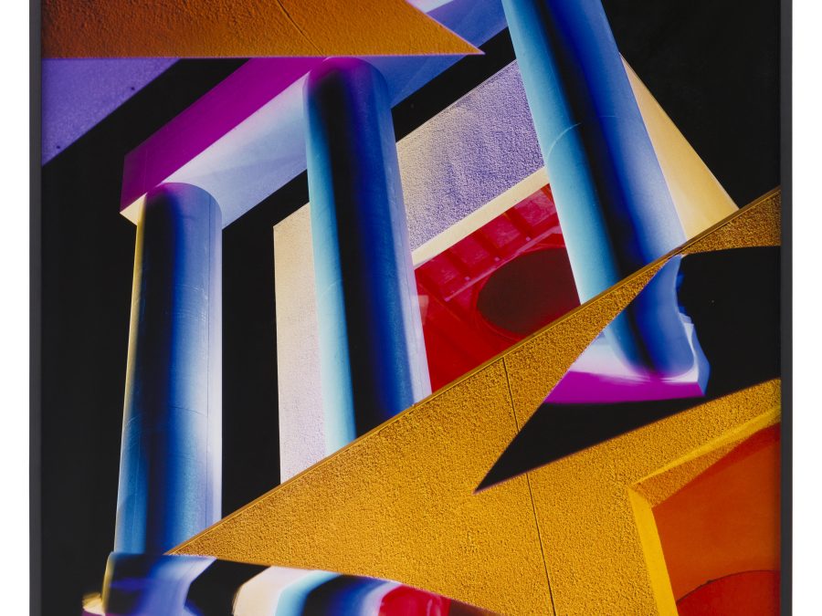 Collage of colorful geometric objects including blue and purple columns and yellow triangles layered on top of each other against a black background