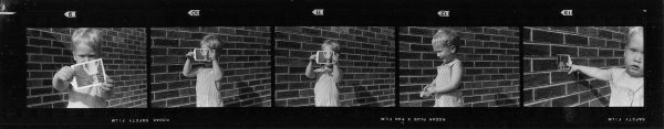 Five images in a contact strip depict a small child holding a photograph in various positions