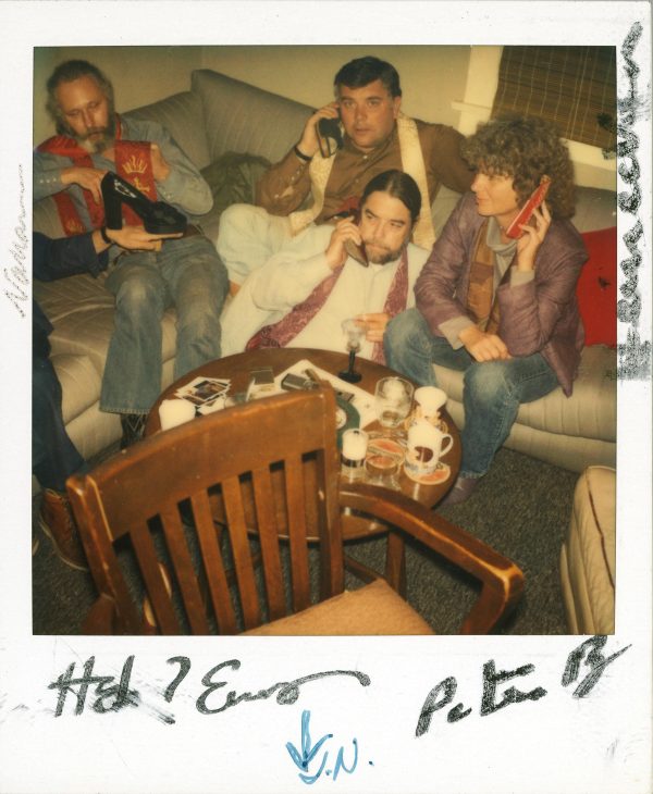 Polaroid of four people hanging out on a couch with illegible writing in the white border