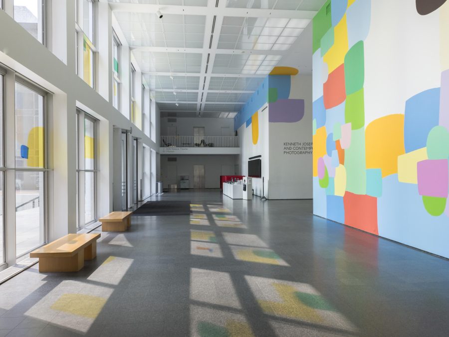 The MCA Atrium features a prominent, colorful mural on multiple walls. Colored panels on the windows create colorful shadows on the floor.