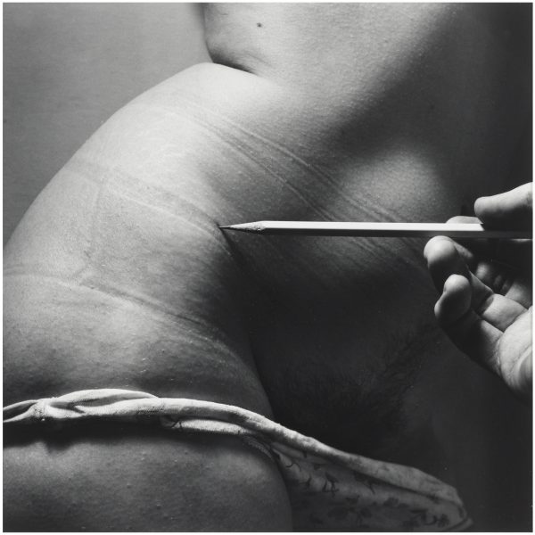 The lower torso of a person with light skin, their underwear rolled down to reveal the top of a tuft of pubic hair. A right hand just barely visible from the right side holds out a pencil and lightly touches it to the person's upper-right hip