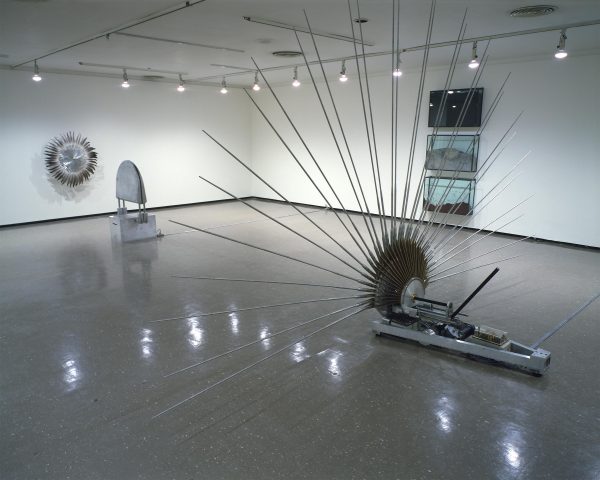 Artworks hang on the floor and rest on the floor in a white gallery space