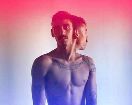 The bare torso of a man with two heads, one seen in profile and the facing forward, in a gradient pink-to-blue backdrop.