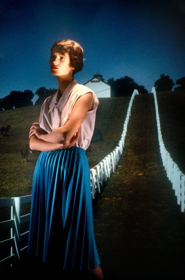 A feminine person with short hair gazes into the distance.