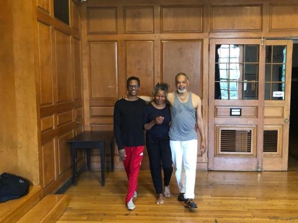 Three people pose in athletic wear in a wood paneled room