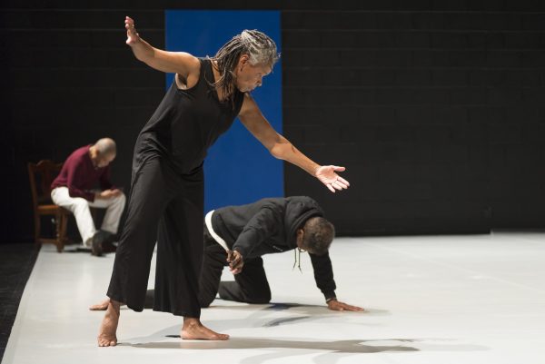 A person with both arms out bends toward a another person crawling on the floor