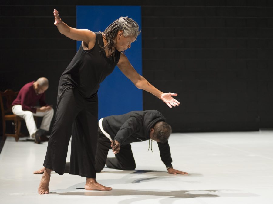 A person with both arms out bends toward a another person crawling on the floor