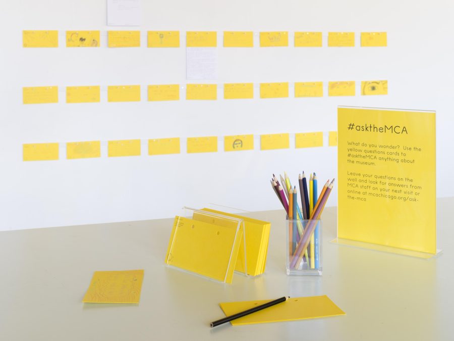 A table with pens and note cards next to a placard with instructions titled Ask the MCA