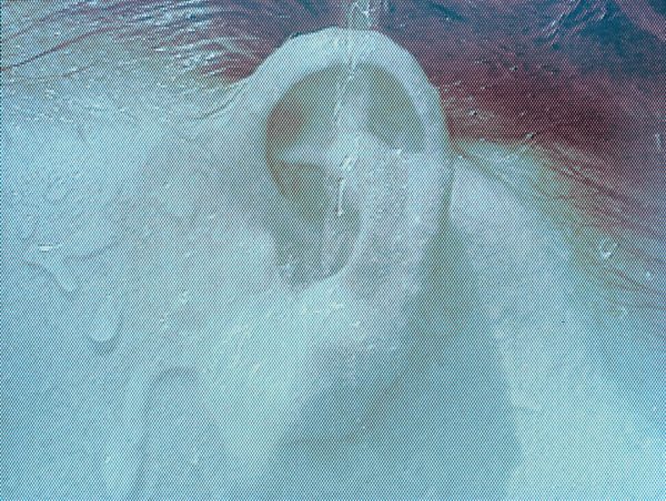 In a blue-tinted image a stream of water pours directly into a person's ear.