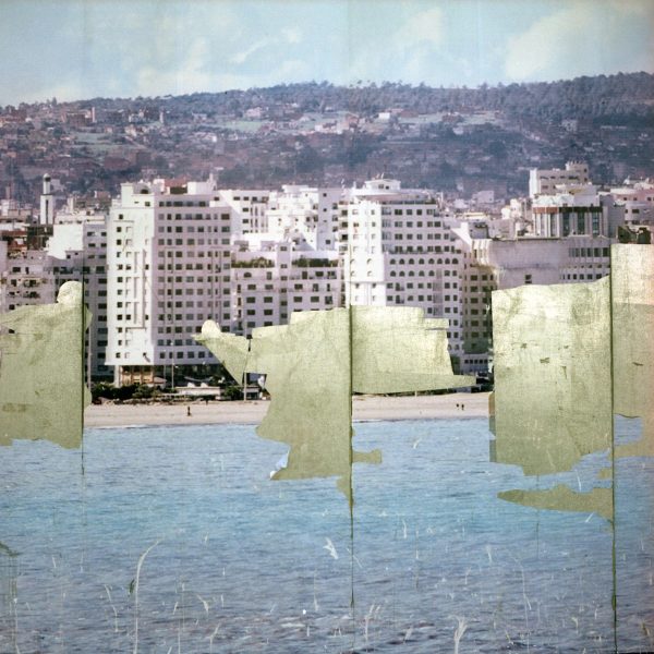 What appears to be a faded, scratched poster displaying tall waterfront residential buildings is missing large sections, as if it peeled off of a wall.