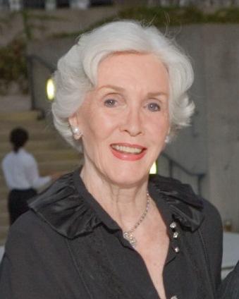Three-quarter portrait of a woman with light skin and wavy white hair styled in a short bob