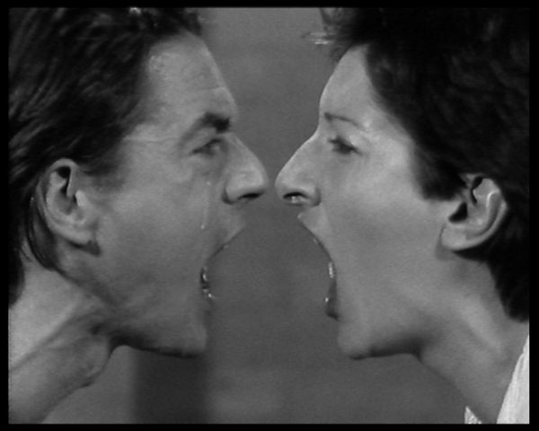 Black and white image of the profile view of two people yelling at each other