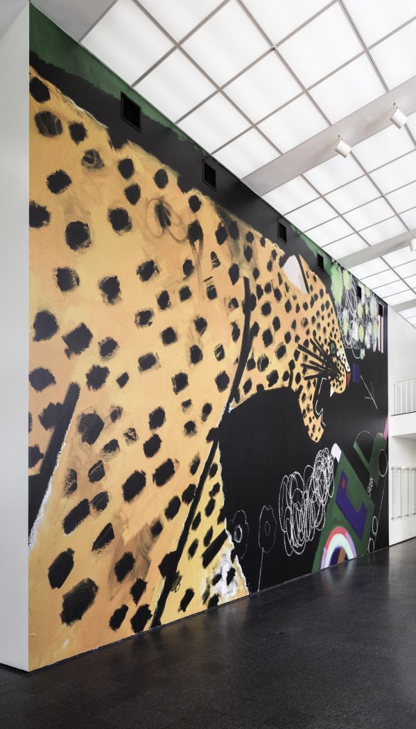 A floor to ceiling mural of a cheetah with their mouth open against a black background