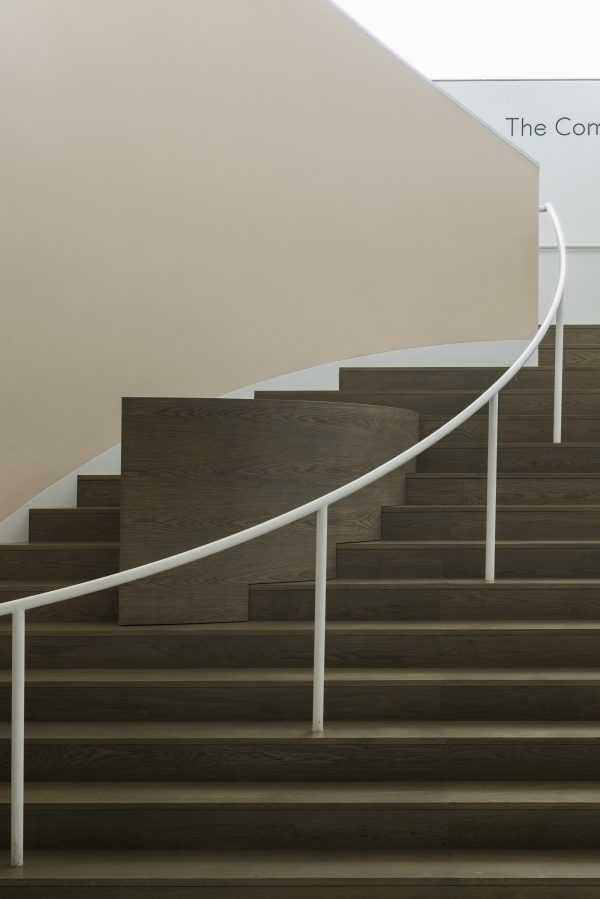 A curved staircase with a white banister that blocks off a wooden structure covering a portion of the steps