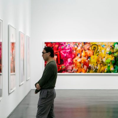 A man stands in profile intently browsing art in gallery