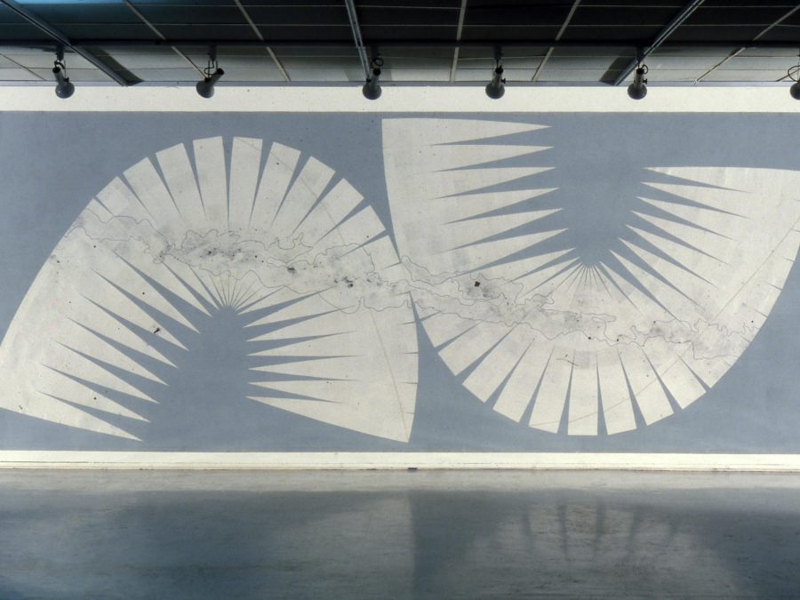 A rectangular large work with a light blue-gray background and a series of white triangles that have been placed together so closely that they make up two shapes that look like a lowercase n and a U.